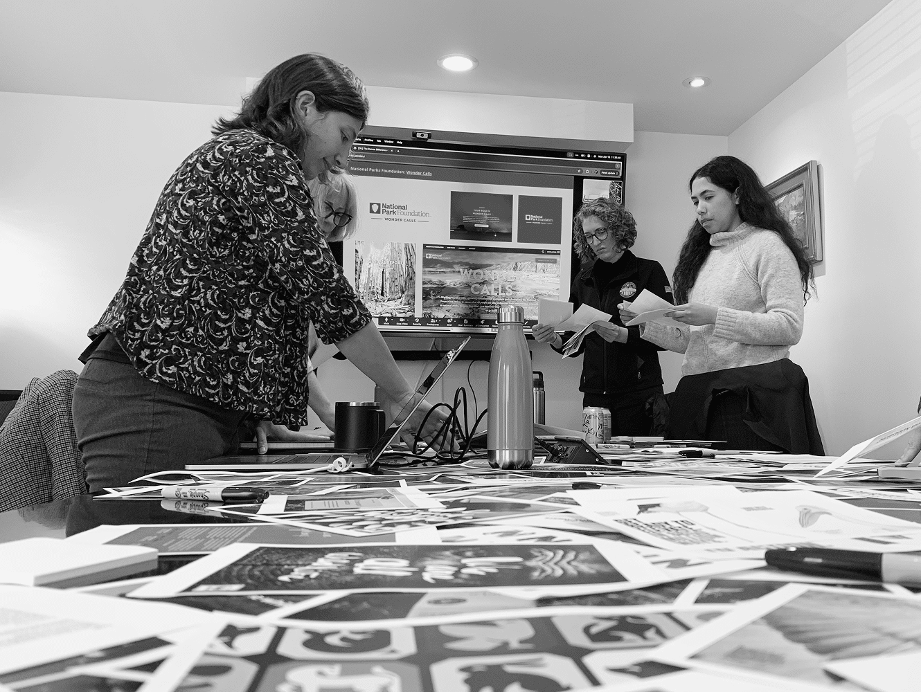 Group of people collaborating around a table covered with photographs and design materials.