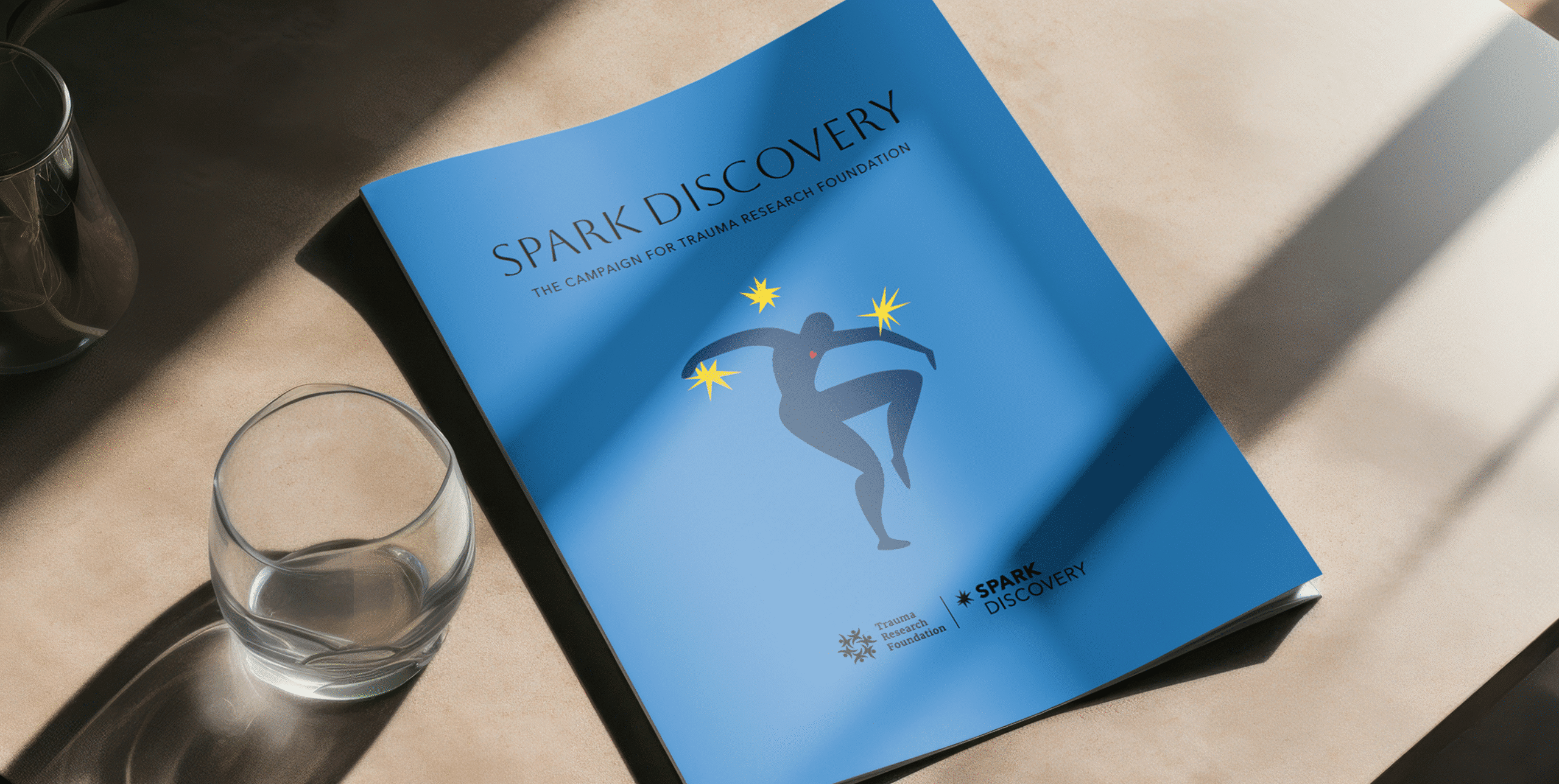 Blue campaign case booklet titled “Spark Discovery” with abstract figure and yellow starbursts.