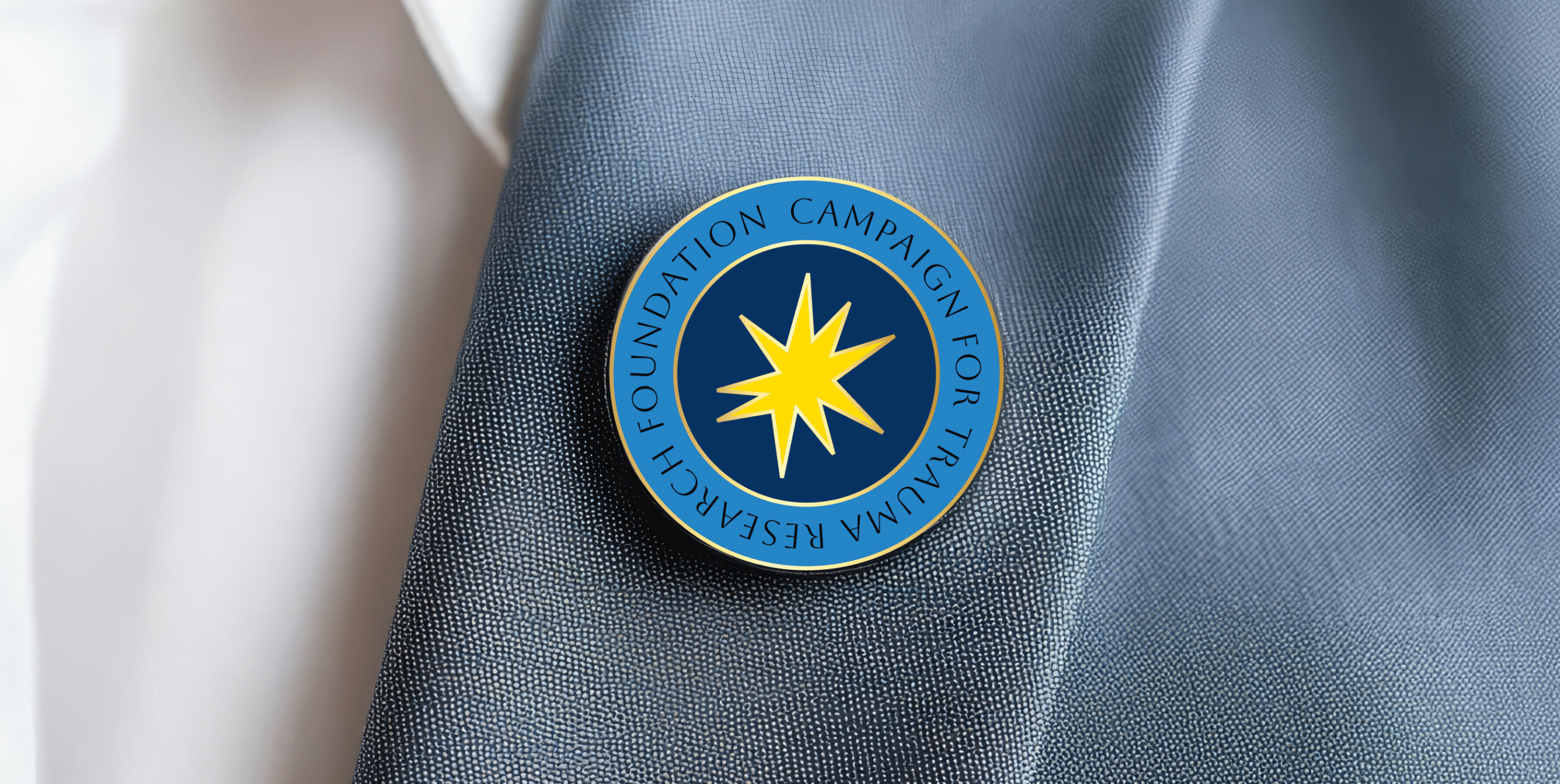 Round campaign lapel pin with yellow starburst on a blue suit jacket.